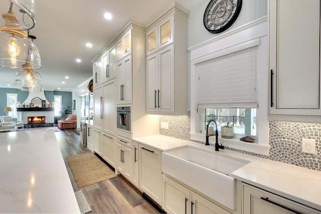 kitchen featuring light stone countertops, tasteful backsplash, dark wood-type flooring, hanging light fixtures, and oven