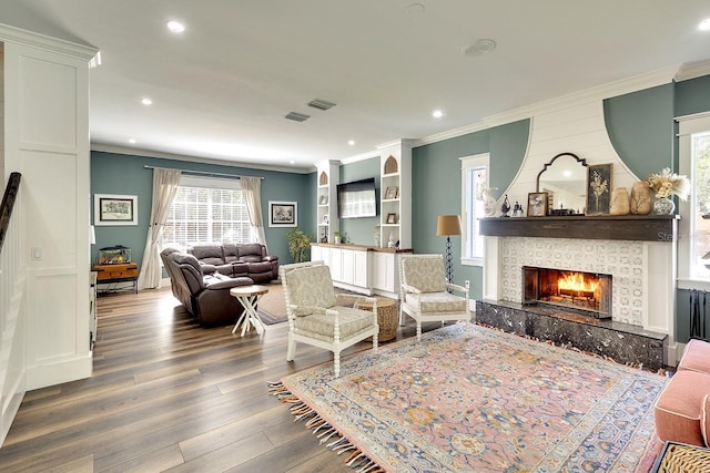 living room featuring crown molding, dark hardwood / wood-style floors, and a tile fireplace