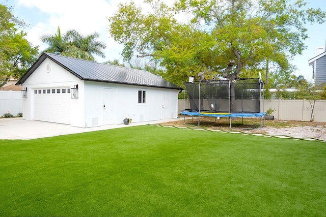 view of yard with an outdoor structure, a trampoline, and a garage