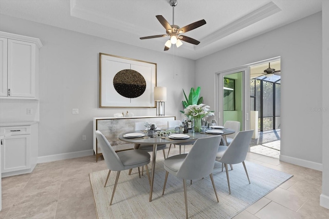 tiled dining area with a raised ceiling and ceiling fan