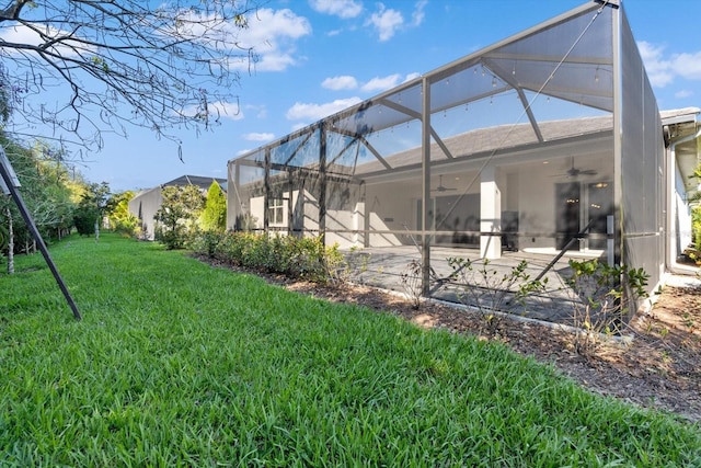 back of house with glass enclosure, ceiling fan, a patio area, and a yard