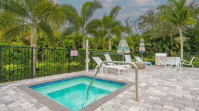 view of swimming pool with grilling area, a community hot tub, and a patio