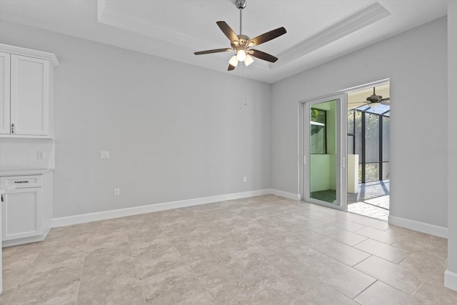 tiled spare room with a tray ceiling and ceiling fan