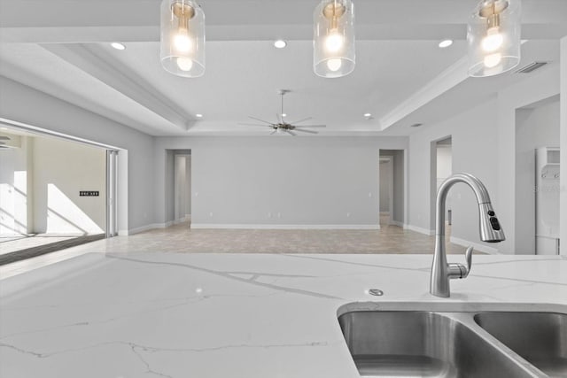 kitchen with a tray ceiling, crown molding, sink, and pendant lighting