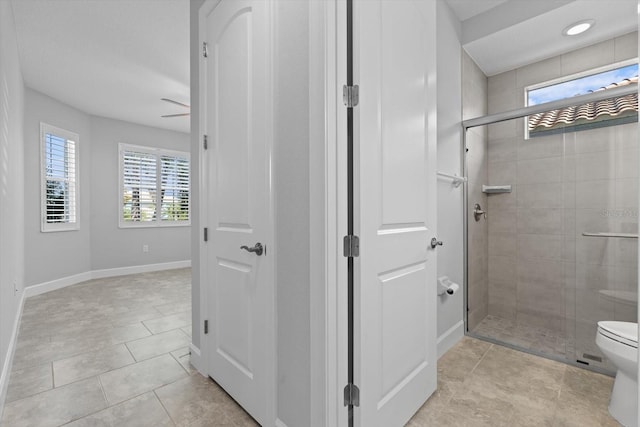 bathroom with tile patterned floors, ceiling fan, a shower with door, and toilet