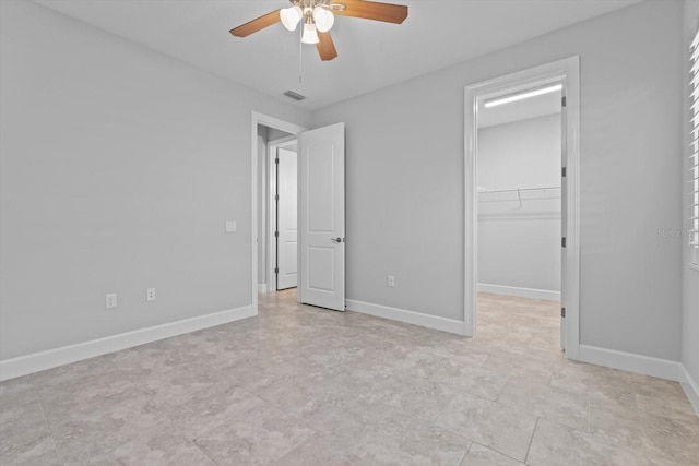 unfurnished bedroom featuring a walk in closet, a closet, and ceiling fan