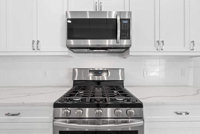 kitchen featuring tasteful backsplash, light stone countertops, white cabinets, and stainless steel appliances