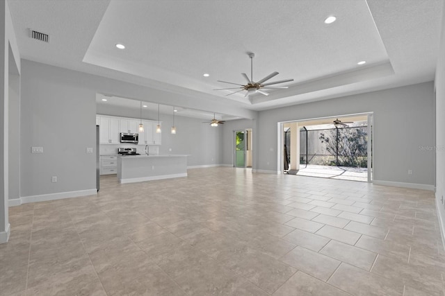 unfurnished living room featuring a textured ceiling, a wealth of natural light, and a tray ceiling