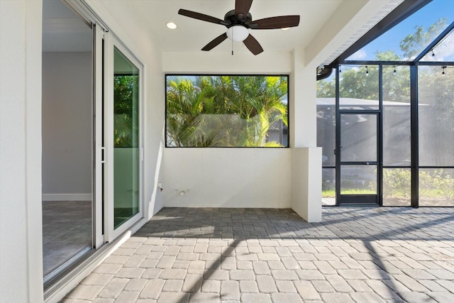 unfurnished sunroom featuring ceiling fan and a healthy amount of sunlight