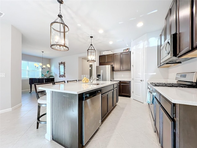 kitchen featuring appliances with stainless steel finishes, sink, an inviting chandelier, hanging light fixtures, and an island with sink