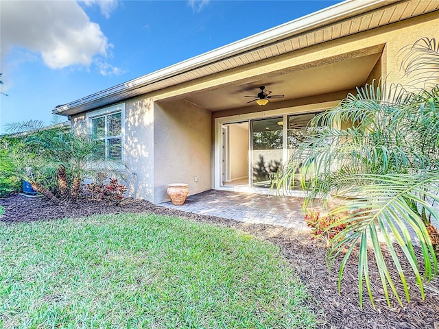 doorway to property featuring a lawn and ceiling fan