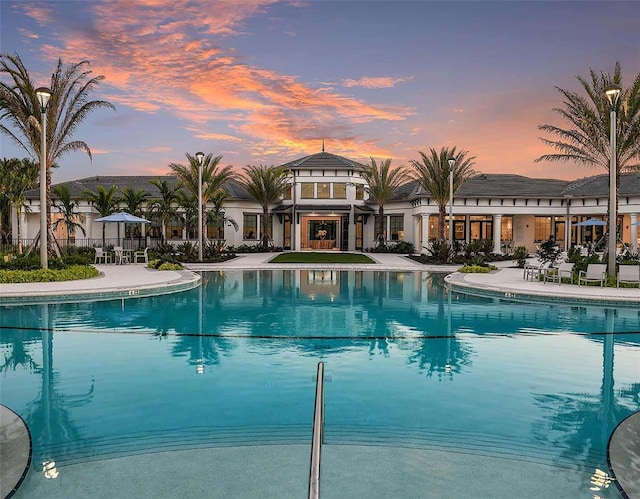 pool at dusk with a patio area