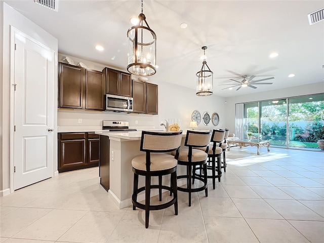 kitchen featuring dark brown cabinets, pendant lighting, stainless steel appliances, and ceiling fan with notable chandelier