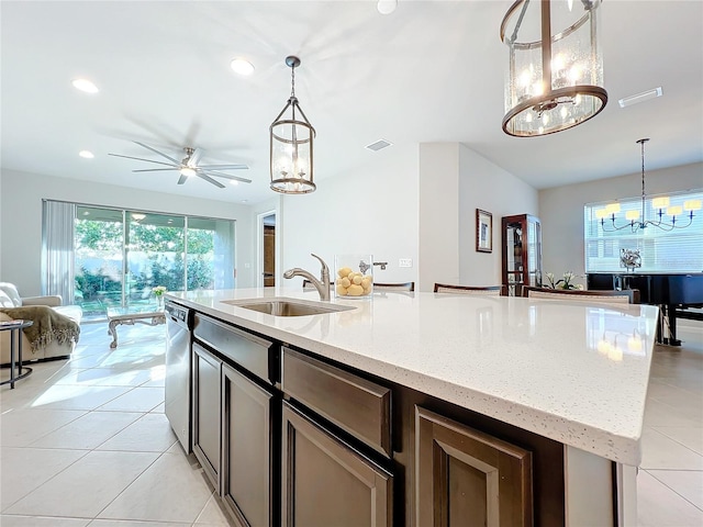 kitchen with light stone countertops, ceiling fan with notable chandelier, sink, pendant lighting, and dishwasher