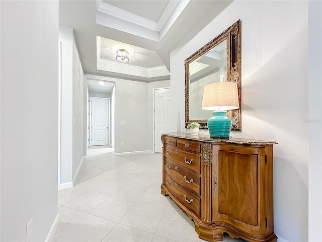 hallway with a raised ceiling, light tile patterned floors, and crown molding