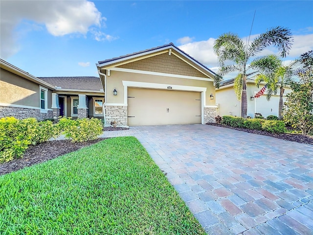 craftsman house featuring decorative driveway, stone siding, an attached garage, a front lawn, and stucco siding