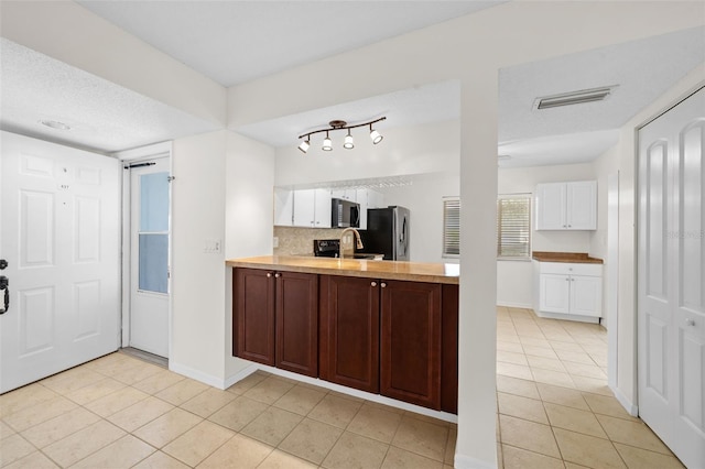 kitchen with backsplash, sink, light tile patterned floors, appliances with stainless steel finishes, and white cabinetry