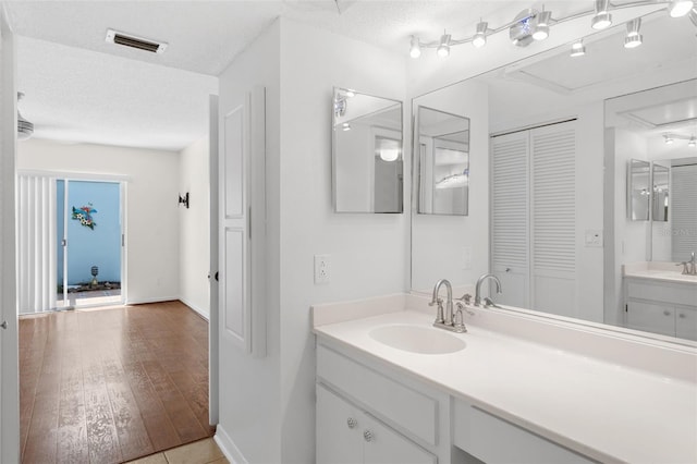 bathroom with vanity, wood-type flooring, and a textured ceiling