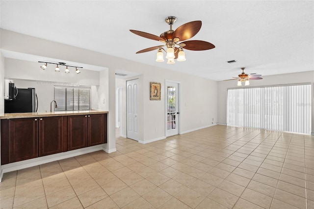 unfurnished living room featuring ceiling fan, sink, and light tile patterned floors