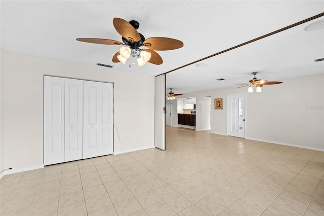 unfurnished living room with ceiling fan and a textured ceiling