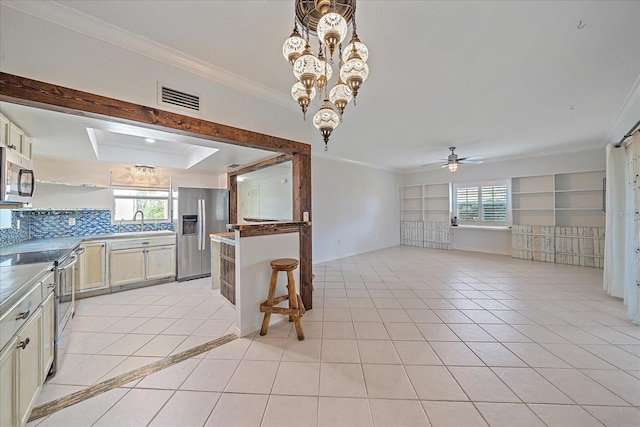 kitchen featuring light tile flooring, plenty of natural light, stainless steel appliances, and ceiling fan with notable chandelier