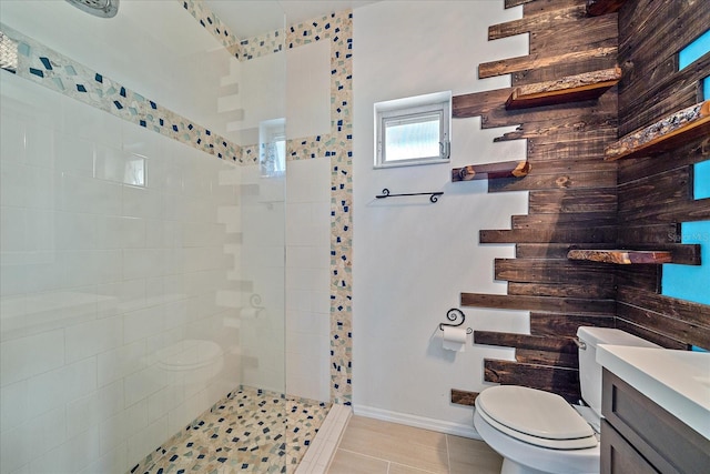 bathroom featuring toilet, tile floors, vanity, and tiled shower