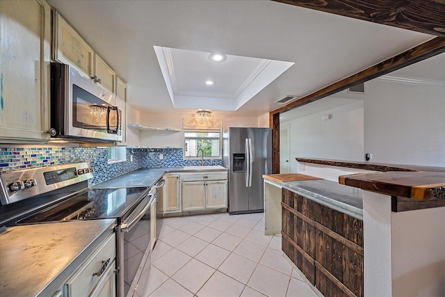 kitchen featuring sink, light tile floors, stainless steel appliances, a tray ceiling, and tasteful backsplash