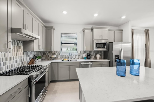 kitchen with appliances with stainless steel finishes, gray cabinetry, backsplash, and sink