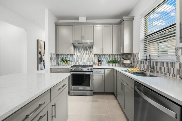 kitchen featuring appliances with stainless steel finishes, sink, light tile floors, tasteful backsplash, and gray cabinets