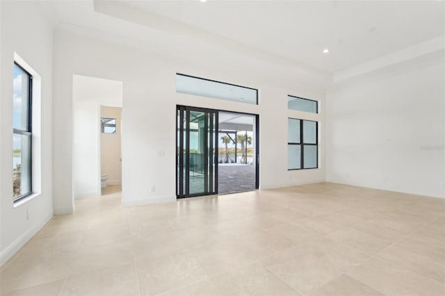 empty room with light tile patterned floors and a towering ceiling