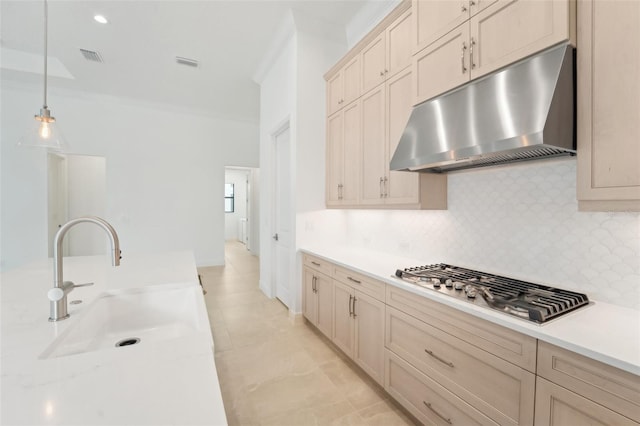 kitchen featuring sink, hanging light fixtures, stainless steel gas stovetop, decorative backsplash, and ornamental molding