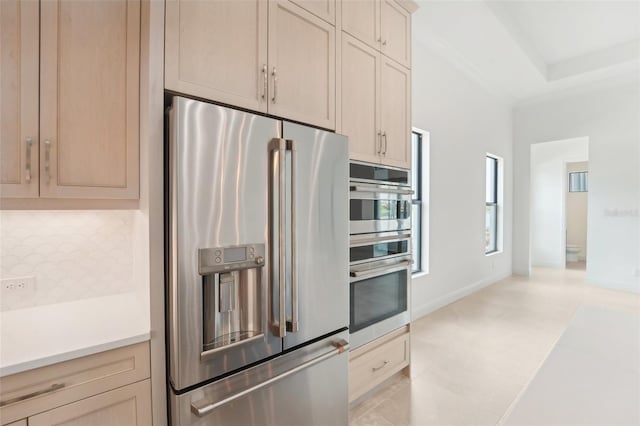 kitchen with light brown cabinets, stainless steel appliances, and tasteful backsplash