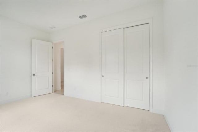 unfurnished bedroom with a closet and light colored carpet