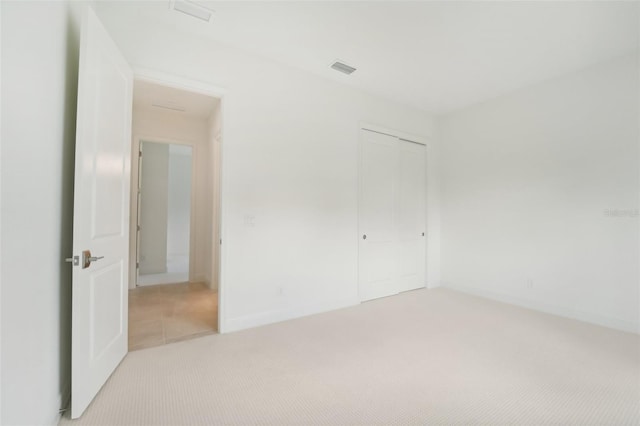 unfurnished bedroom featuring light colored carpet and a closet