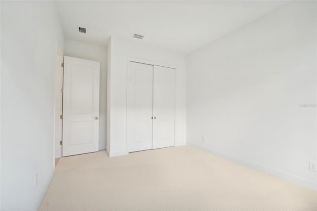 unfurnished bedroom featuring light carpet and a closet