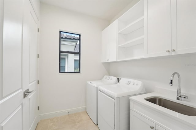 laundry room with cabinets, light tile patterned floors, separate washer and dryer, and sink