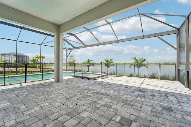 view of patio / terrace featuring glass enclosure, a swimming pool with hot tub, and a water view