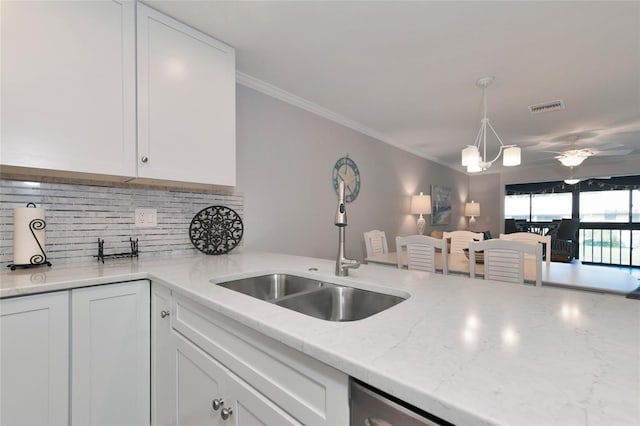 kitchen with light stone countertops, sink, white cabinetry, and ceiling fan with notable chandelier