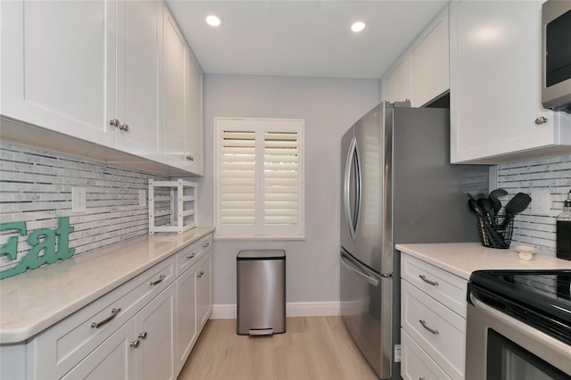 kitchen featuring light stone countertops, white cabinetry, light hardwood / wood-style floors, stainless steel appliances, and tasteful backsplash