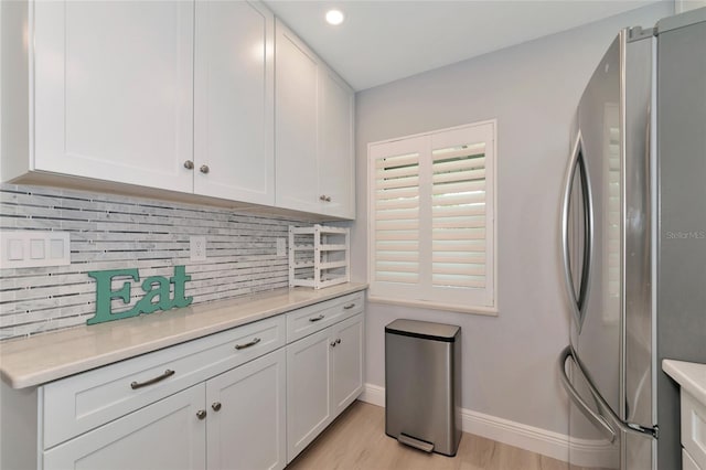 kitchen featuring light hardwood / wood-style floors, white cabinetry, backsplash, and stainless steel refrigerator