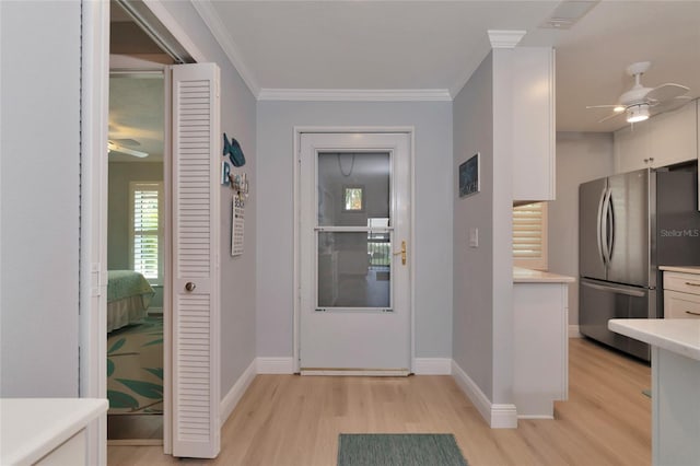 foyer featuring ornamental molding, ceiling fan, and light wood-type flooring