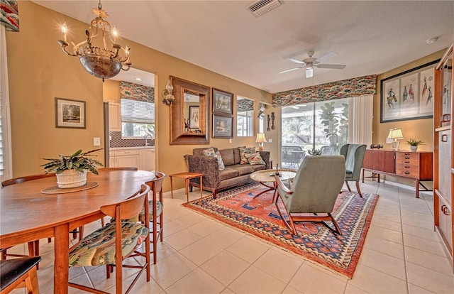 living room with ceiling fan with notable chandelier and light tile floors