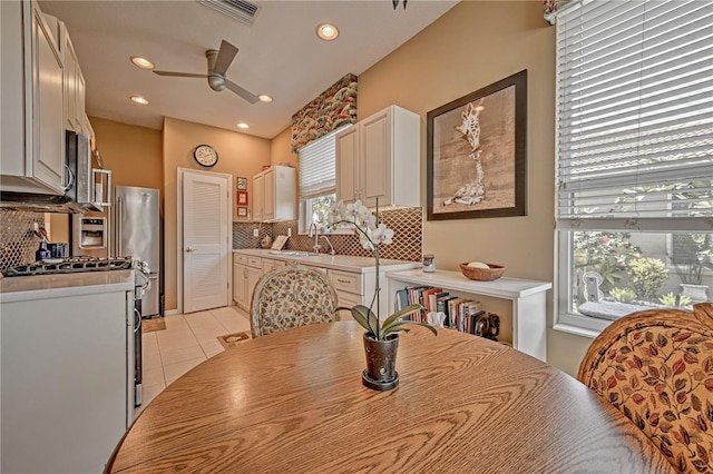 dining room with plenty of natural light, sink, ceiling fan, and light tile floors