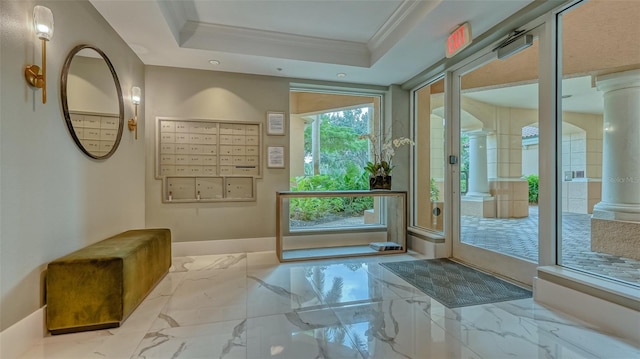 doorway with decorative columns, a tray ceiling, and light tile flooring