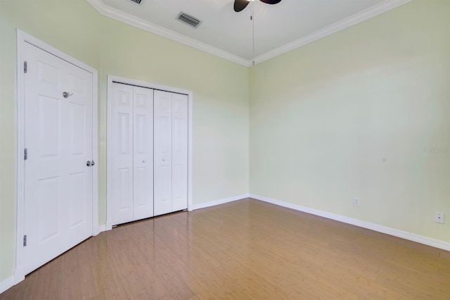 unfurnished bedroom with crown molding, hardwood / wood-style floors, a closet, and ceiling fan