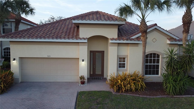 mediterranean / spanish home with a garage, decorative driveway, a tile roof, and stucco siding