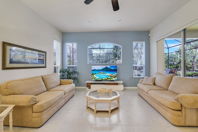 living area with light tile patterned floors, baseboards, and a ceiling fan