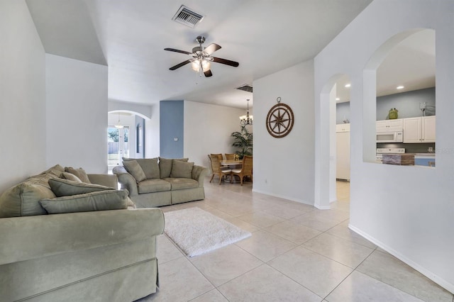 living room featuring light tile patterned floors, visible vents, arched walkways, a ceiling fan, and baseboards