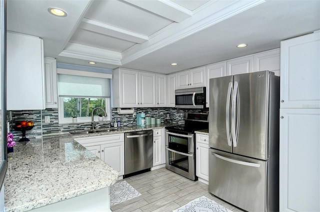 kitchen with tasteful backsplash, white cabinetry, appliances with stainless steel finishes, and light stone counters