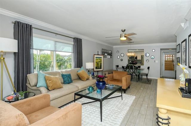 living room with light hardwood / wood-style floors, ornamental molding, and ceiling fan